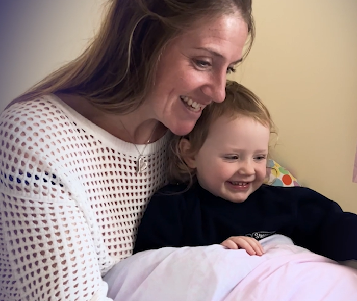 Mother and daughter seated together laughing.